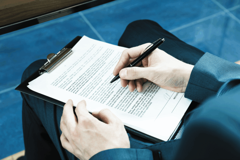 Mężczyzna podpisujący dokumenty prawne, ilustrujący analizę umów przez radcę prawnego.